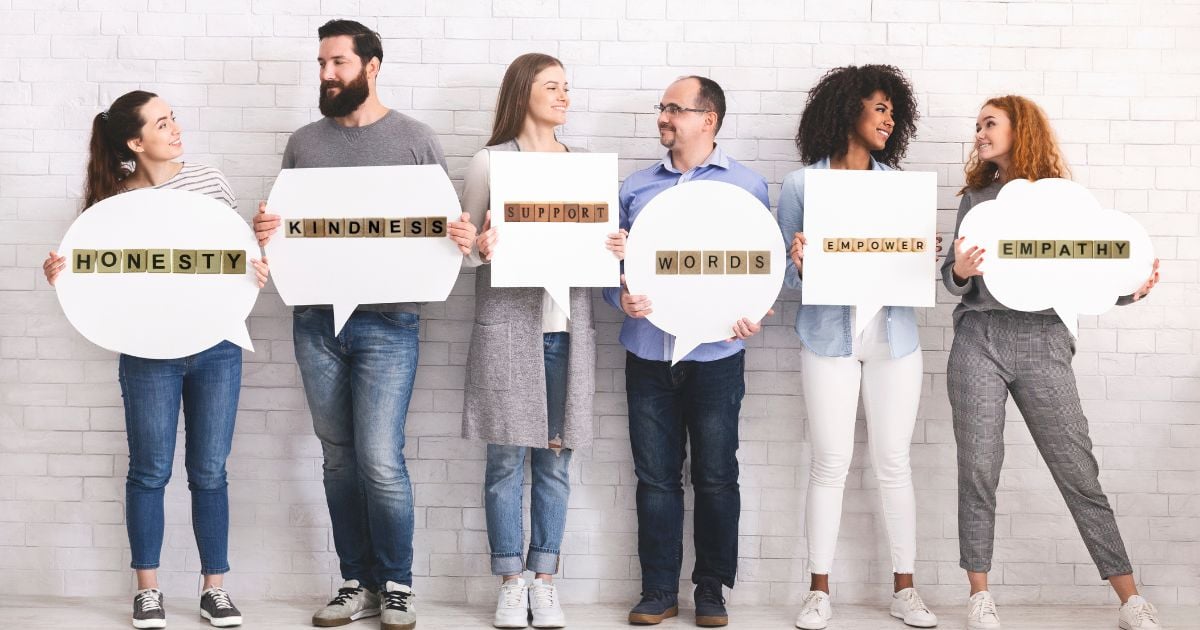 A group of different people holding up speech bubbles with words like honesty, kindness, empathy.