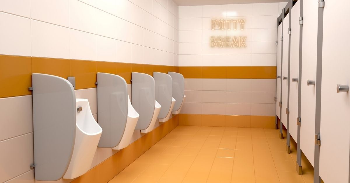 Empty orange colored bathroom with stalls and urinals